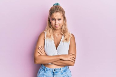 Gündelik kıyafetler giyen, kuşkucu ve gergin genç sarışın bir kız. Yüzünde çapraz kollarla onaylamayan bir ifade var. negatif kişi. 