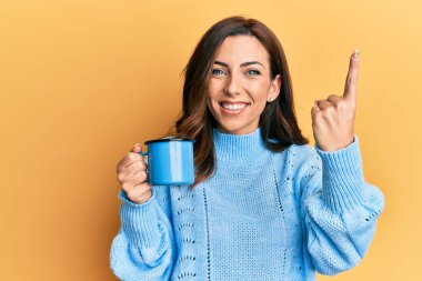 Genç esmer kadın elinde kahve fincanı tutarken bir fikir ya da soruyla şaşırdı. 