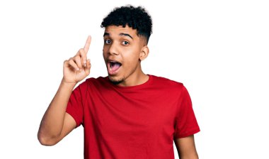 Gündelik kırmızı t-shirt giyen genç Afro-Amerikan adam başarılı bir fikri işaret ediyor. Heyecanlı ve mutlu. Bir numara.. 