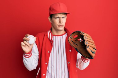 Beyzbol üniforması giyen yakışıklı beyaz adam Golve 'u tutuyor ve topları kuşkucu ve sinirli, sorun yüzünden surat asıyor. negatif kişi. 