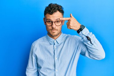 Sıradan kıyafetler ve gözlük takan genç İspanyol adam alnındaki sivilceden mutsuz olduğunu gösteriyor. Siyah noktalı çirkin bir enfeksiyon. sivilce ve deri problemi 