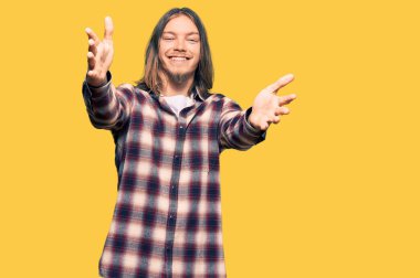 Uzun saçlı, hippi gömleği giyen yakışıklı beyaz adam kameraya bakıp sarılmak için gülümsüyor. Mutluluğu kucaklayan neşeli bir ifade.. 