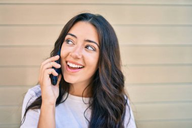 Genç İspanyol kadın gülümsüyor. Şehirdeki akıllı telefondan konuşuyor..