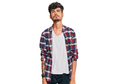 Günlük kıyafetler giyen genç İspanyol adam yüzünde ciddi bir ifadeyle rahatlamış. Basit ve doğal bir şekilde kameraya bakıyorsun.. 