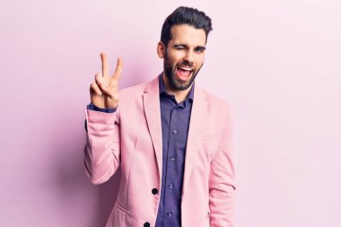 Sakallı, zarif ceketli, gülümseyen, kameraya göz kırpan, zafer işareti yapan yakışıklı bir genç. İki numara.. 