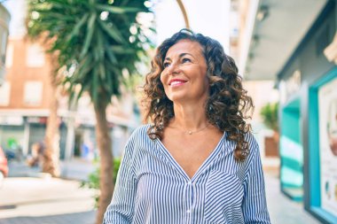 Orta yaşlı İspanyol kadın gülümseyerek şehirde mutlu mesut yürüyor..