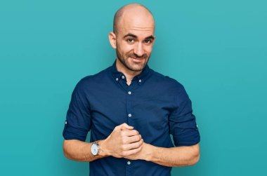 Latin asıllı genç adam ellerinin birleştiği günlük kıyafetler giyiyor ve gülümseyerek gevşemiş ve neşeli gülümsüyor. Başarı ve iyimserlik 