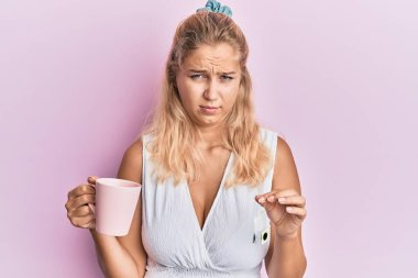 Elinde çay fincanı tutan genç sarışın kız şüpheci ve gergin, sorun yüzünden surat asıyor. negatif kişi. 