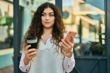 Genç İspanyol kadın akıllı telefon kullanıyor ve şehirde kahve içiyor..