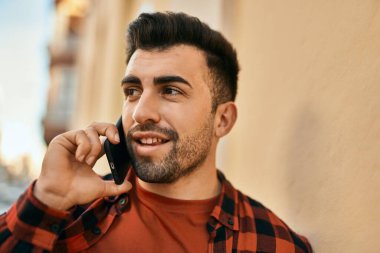 Genç İspanyol adam gülümsüyor. Şehirdeki akıllı telefondan konuşuyor..