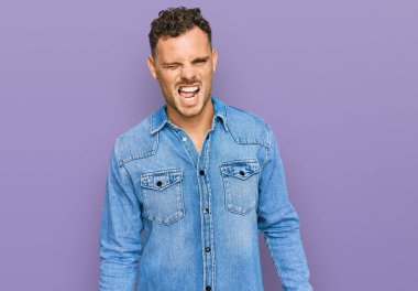 Sıradan kot ceket giyen genç İspanyol adam kameraya seksi bir ifadeyle bakıyor, neşeli ve mutlu bir yüz.. 