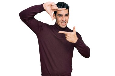 Yakışıklı, balıkçı yaka kazak giyen, gülümseyen, elleri ve parmakları gülen yüzlü İspanyol bir adam. yaratıcılık ve fotoğrafçılık kavramı. 