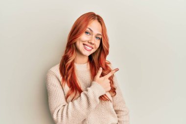 Genç, güzel, kızıl saçlı, günlük süveter giyen, neşeli, yüzünde mutlu ve doğal bir ifadeyle, elleri ve parmaklarıyla yüzünü gösteren bir gülümseme olan bir kadın. 