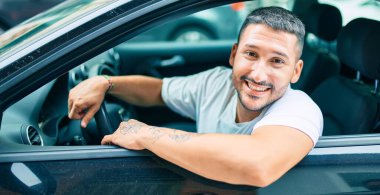 Gülümseyen İspanyol genç adam mutlu araba kullanıyor..