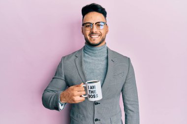 Genç Arap adam benden içiyor patron kahve fincanı pozitif ve mutlu görünüyor kendine güvenen bir gülümsemeyle dişlerini gösteriyor. 