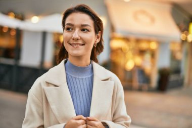 Genç İspanyol kadın gülümseyerek şehirde mutlu mesut dikiliyor.