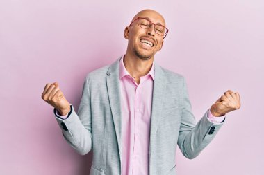 Sakallı, iş elbiseleri ve gözlüklü, mutlu ve heyecanlı bir adam kolları havada, gülümseyen ve başarı için bağıran, kazanan bir jest yapıyor. kutlama konsepti. 