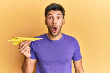 Elinde kağıt uçak tutan genç yakışıklı adam şaşıracak şekilde ağzı açık kalmış, korkmuş ve hayrete düşmüştü. 