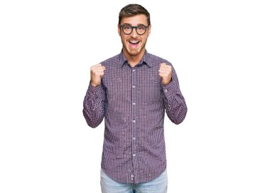 Sıradan kıyafetler ve gözlük takan yakışıklı beyaz adam kollarını kaldırarak ve açık gözlerle başarıyı kutluyor ve şaşırıyor. Kazanan konsept. 
