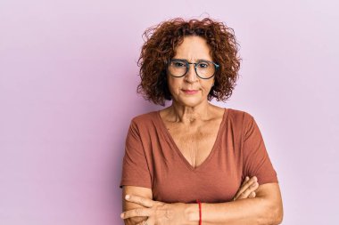 Güzel, orta yaşlı, sıradan kıyafetler giyen, gözlüklü, kuşkucu ve gergin, yüzünde çapraz kollu tasvip etmeyen bir ifade olan olgun bir kadın. negatif kişi. 