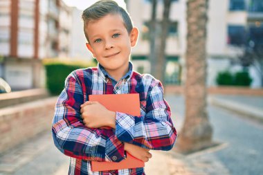 Sevimli beyaz çocuk gülümsüyor. Mutlu bir şekilde elinde kitap tutuyor..
