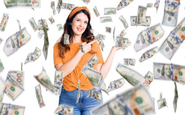 Güzel, genç, esmer, sıradan kıyafetler giyen kadın kameraya hayret ediyor ve gülümsüyor..