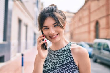 Kafkasyalı genç iş kadını gülümsüyor. Şehirdeki akıllı telefondan mutlu bir şekilde konuşuyor..