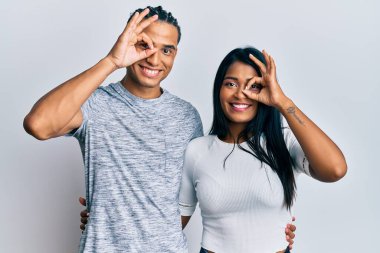 Gündelik kıyafetler giyen genç latin çift el hareketleriyle gülümsüyor, gözleriyle mutlu yüzlerine bakıyor.. 