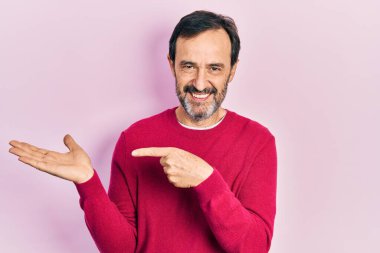 Orta yaşlı İspanyol bir adam gündelik giysiler giyip kameraya hayret ediyor ve gülümsüyor.. 