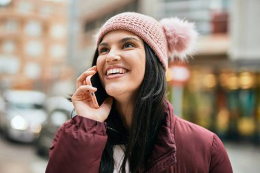 Genç İspanyol kız gülümsüyor. Şehirdeki akıllı telefondan konuşuyor..
