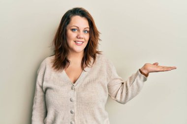 Gündelik kıyafetler giyen, neşeli gülümseyen, avuç içi kameraya bakan beyaz bir kadın.. 