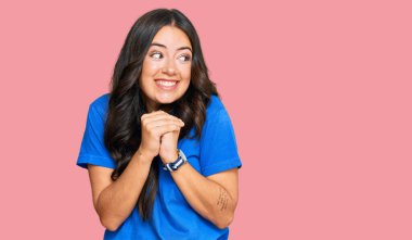 Güzel, esmer, sıradan kıyafetler giyen, gergin ve heyecanlı genç bir kadın. Elleri çenesinde yan tarafa bakıyor. 