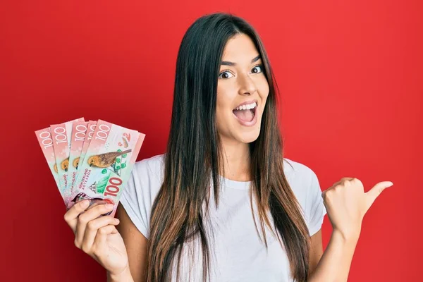 Joven Morena Sosteniendo 100 Nuevos Billetes Zealand Dólares Apuntando Pulgar — Foto de Stock