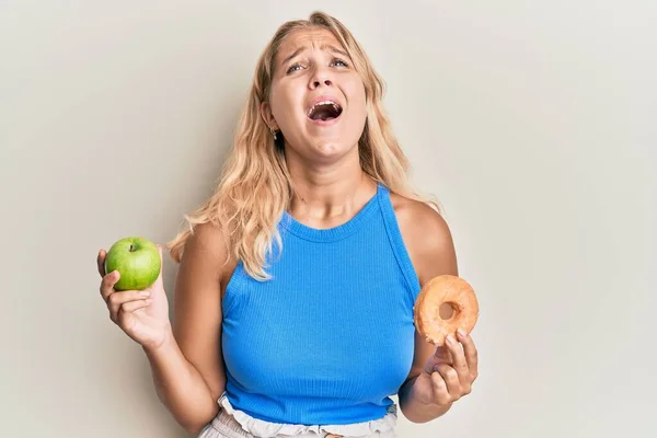 Jong Blond Meisje Met Groene Appel Donut Boos Gek Geschreeuw — Stockfoto