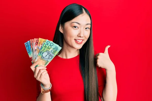 Młoda Chinka Trzyma Australijskie Dolary Uśmiechając Się Szczęśliwy Pozytywny Kciuk — Zdjęcie stockowe