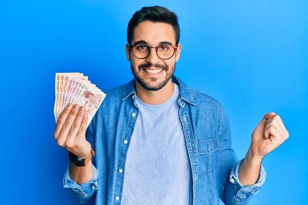 Joven Hispano Sosteniendo Billetes Lira Turca Gritando Orgulloso Celebrando Victoria —  Fotos de Stock