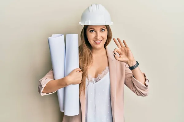 Jonge Blonde Vrouw Draagt Veiligheidshelm Houden Blauwdrukken Doen Teken Met — Stockfoto