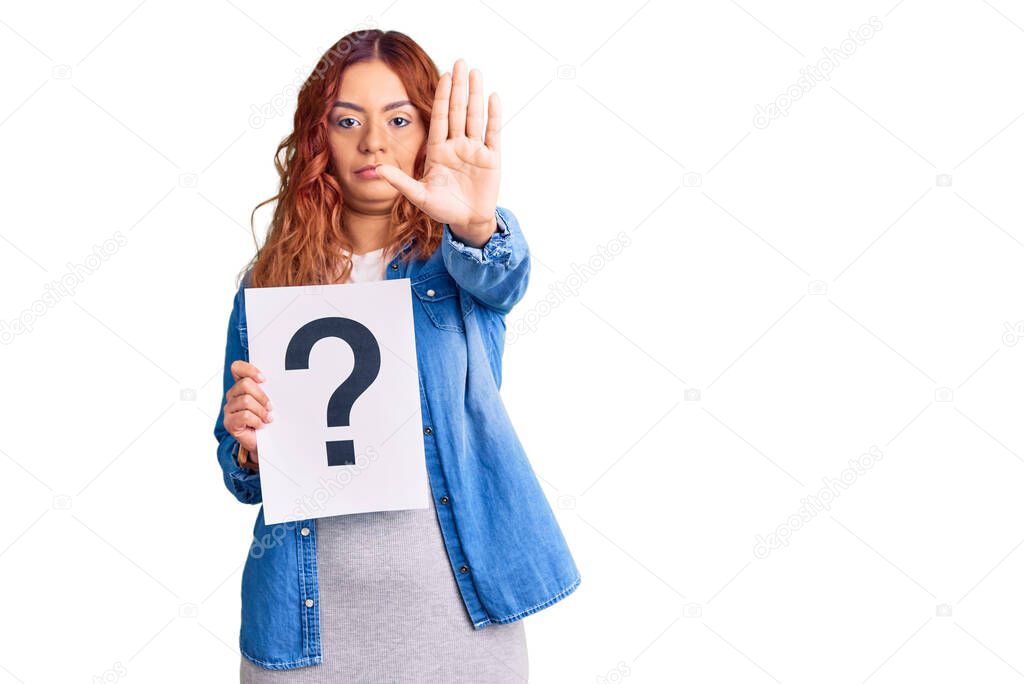 Young latin woman holding question mark with open hand doing stop sign with serious and confident expression, defense gesture 