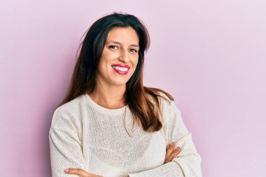 Gündelik kıyafetler giyen, kollarını kavuşturup kameraya gülümseyen güzel İspanyol kadın. pozitif kişi. 