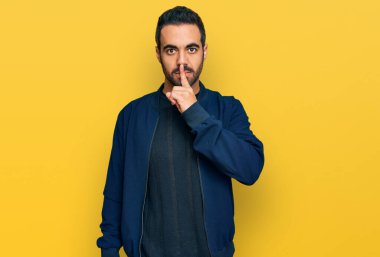 Gündelik kıyafetler giyen genç İspanyol adam parmakları dudaklarında sessiz olmak istiyor. sessizlik ve gizli konsept. 