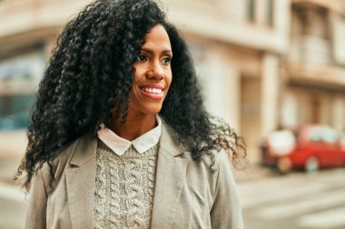 Orta yaşlı Afro-Amerikan iş kadını şehirde mutlu bir şekilde dikilirken gülümsüyor.