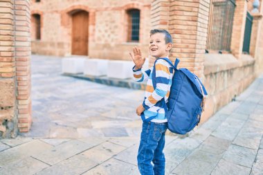 Sevimli beyaz çocuk gülümseyerek okulda el ele vedalaşıyor..