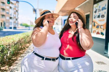 İki tane kilolu abla ikiz kız kardeş güneşli bir günde telefonda konuşan kadınlar.