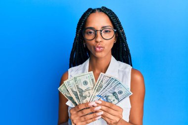 Beautiful hispanic woman holding dollars looking at the camera blowing a kiss being lovely and sexy. love expression. 