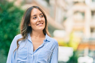 Genç İspanyol kadın gülümseyerek şehirde mutlu mesut dikiliyor..