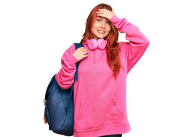 Öğrenci çantası ve kitapları tutan genç, kızıl saçlı bir kadın. Kafası karışık, şaşırmış ve sinirli bir yüzü var. 