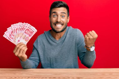 Yakışıklı İspanyol adam Yuan Çin banknotlarını tutuyor gururla bağırıyor, zaferi ve başarıyı kutluyor. 