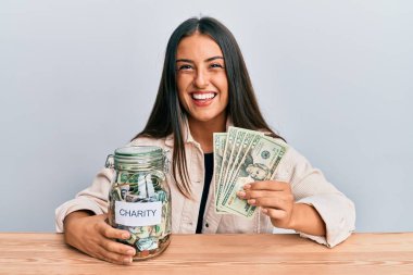 Güzel İspanyol kadın elinde dolarlarla yardım kavanozu tutuyor ve kahkahalarla gülüyor çünkü komik, çılgın bir şaka.. 