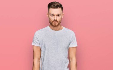 Genç, kızıl saçlı, günlük gri t-shirt giyen bunalımlı ve sıkıntıdan korkan sinirli ve korkmuş bir adam. hüzünlü ifade. 