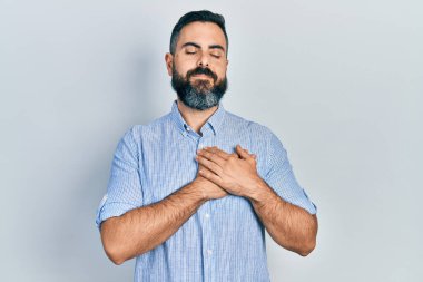 Gündelik kıyafetler giyen genç İspanyol adam elleri göğsünde, gözleri kapalı ve yüzünde minnet dolu bir jest ile gülümsüyor. sağlık kavramı. 